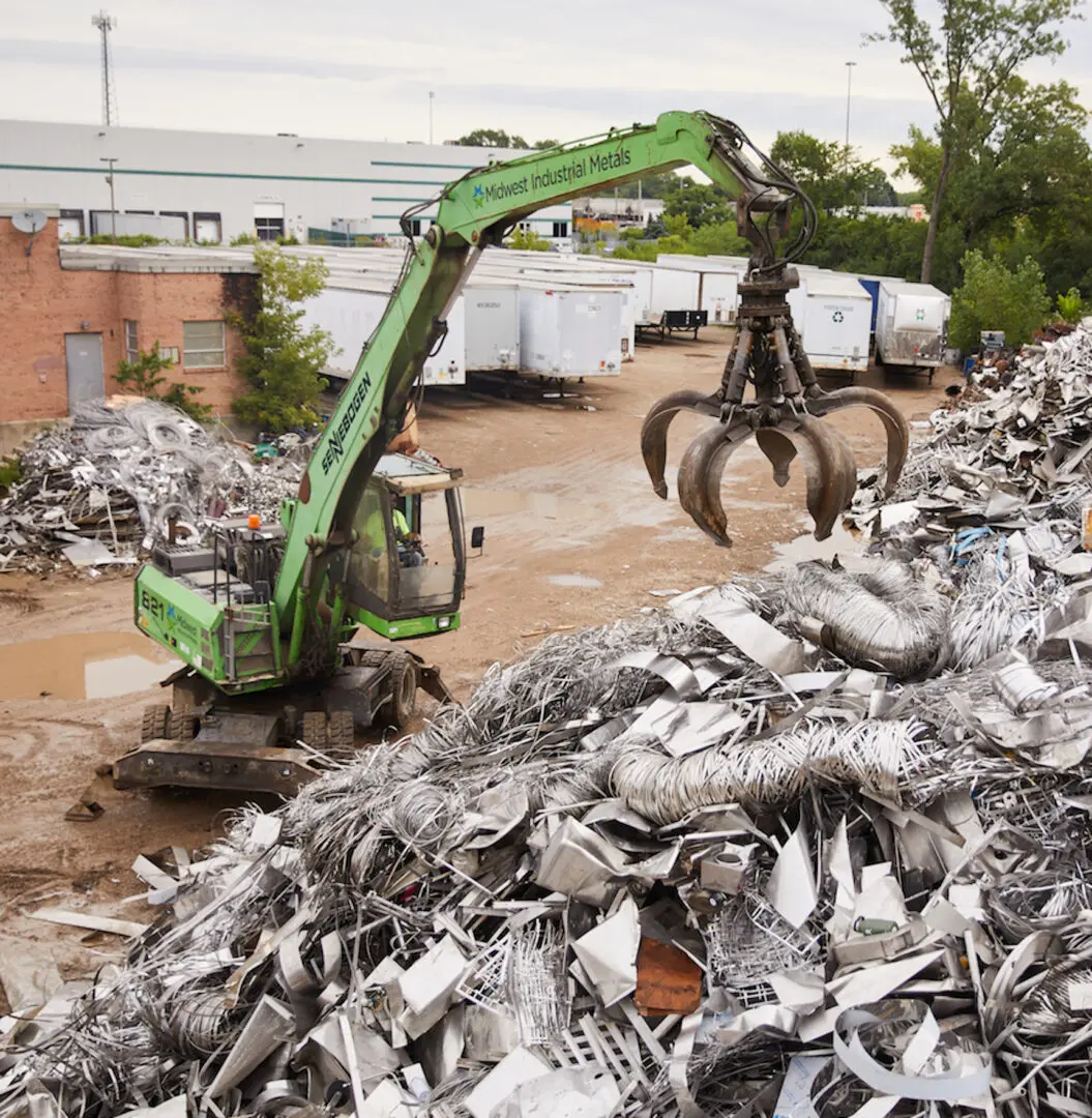 A green machine is in the dirt near some trash.